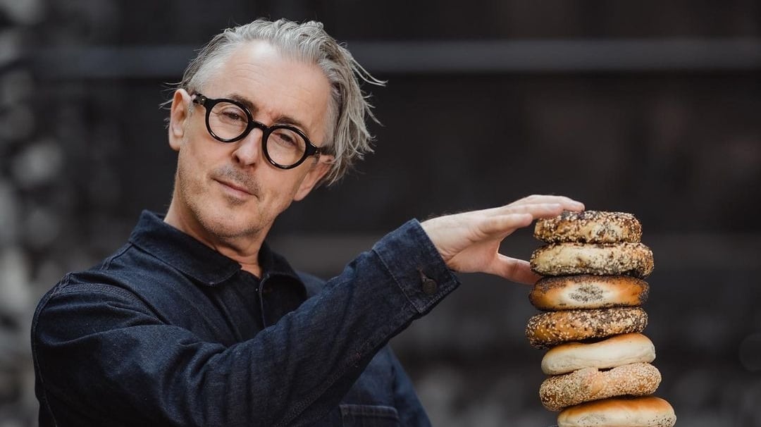 Alan Cumming poses with bagels