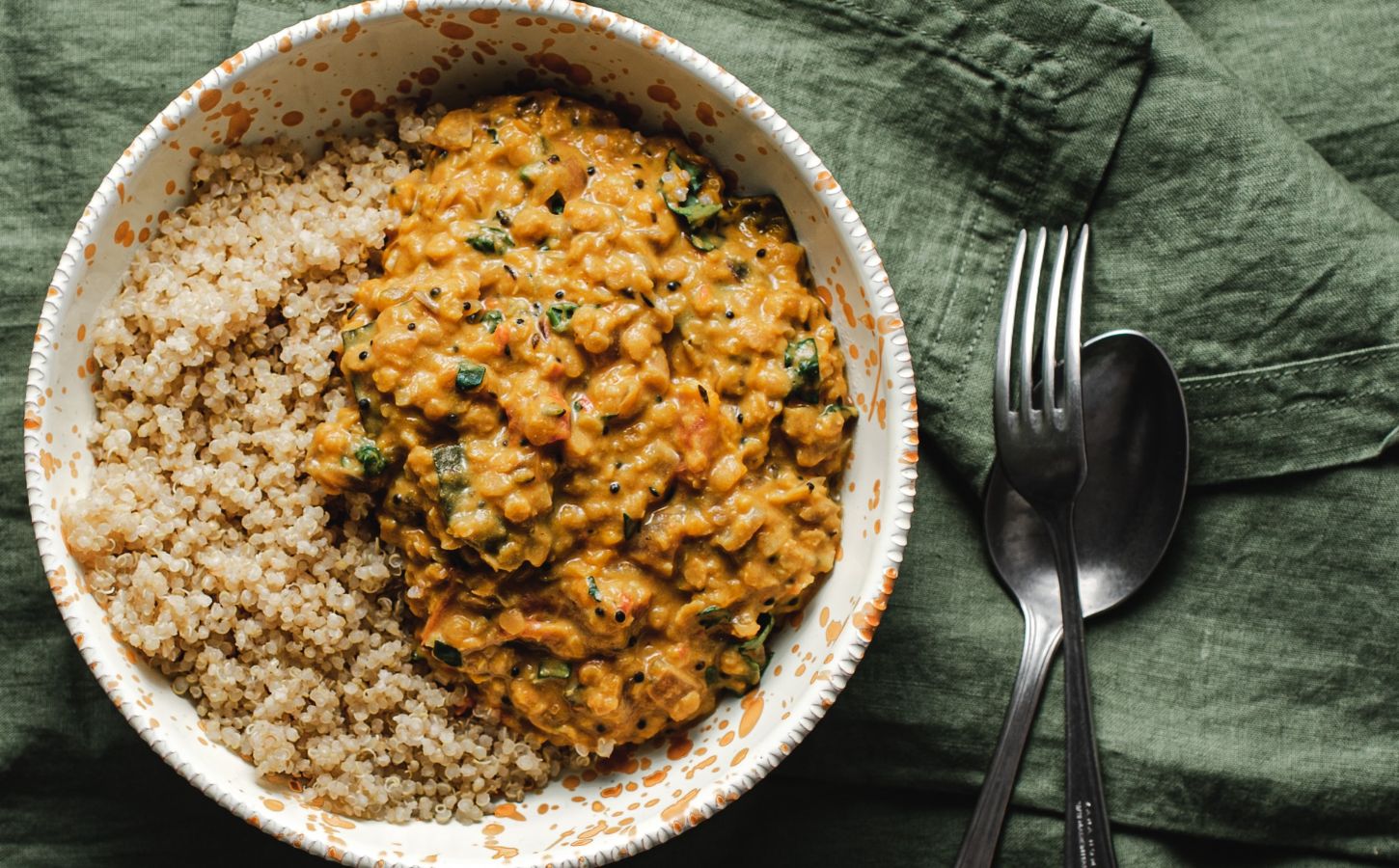 A bowl of butternut squash dahl and grains on a green towel