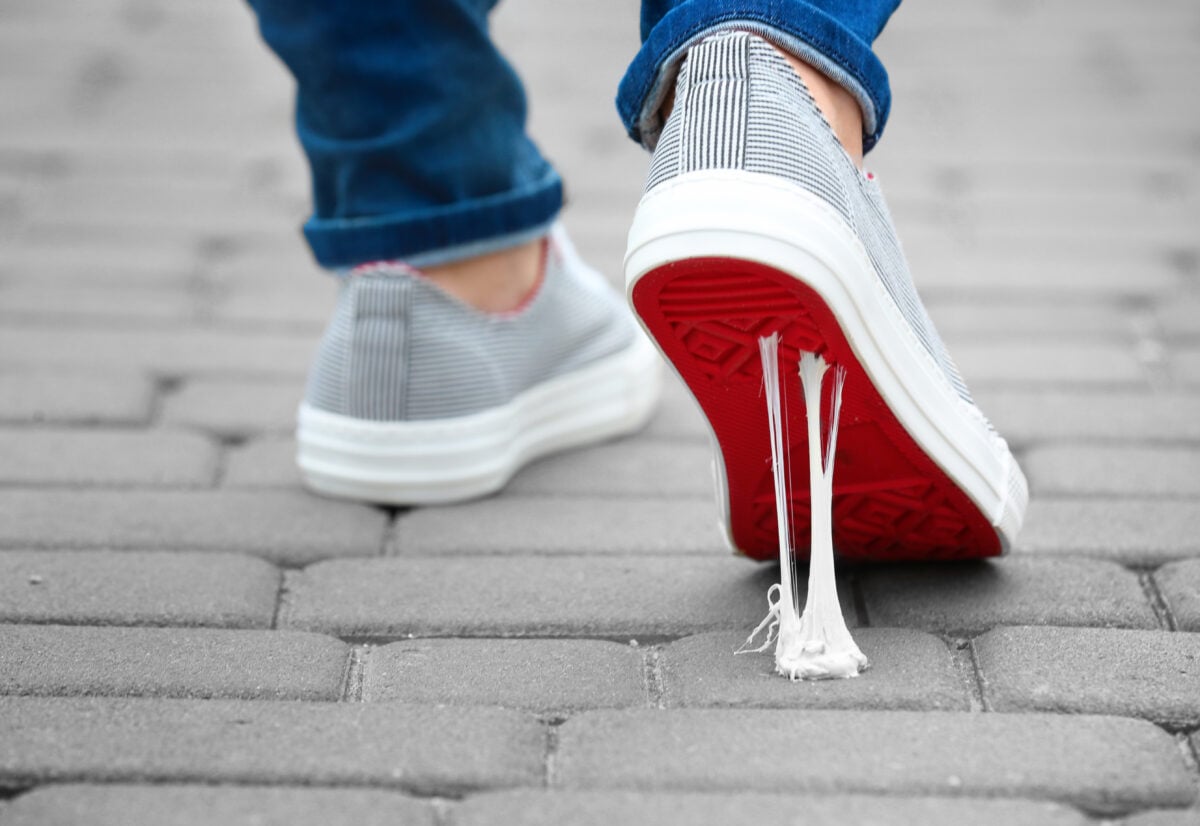 Photo shows someone's foot as they treat in a piece of discarded gum on a cobbled street