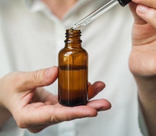 A person holding a dropper containing collagen, which is known to have environmental costs