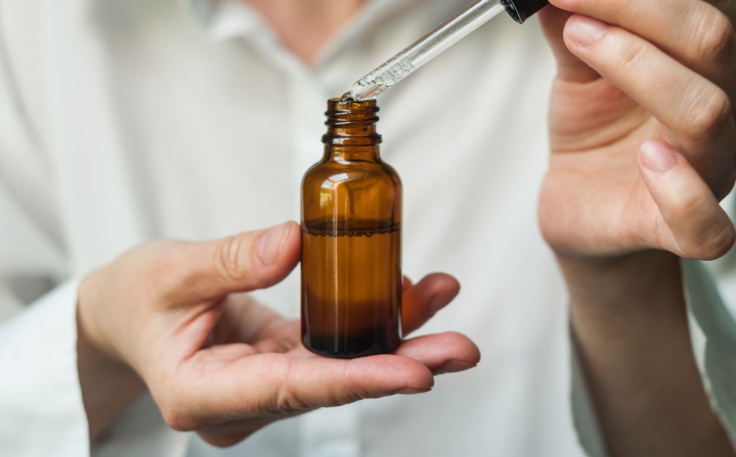 A person holding a dropper containing collagen, which is known to have environmental costs