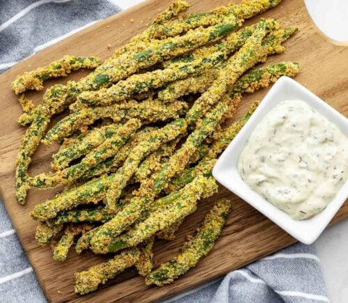 A chopping wooden board covered in oil-free green bean fries