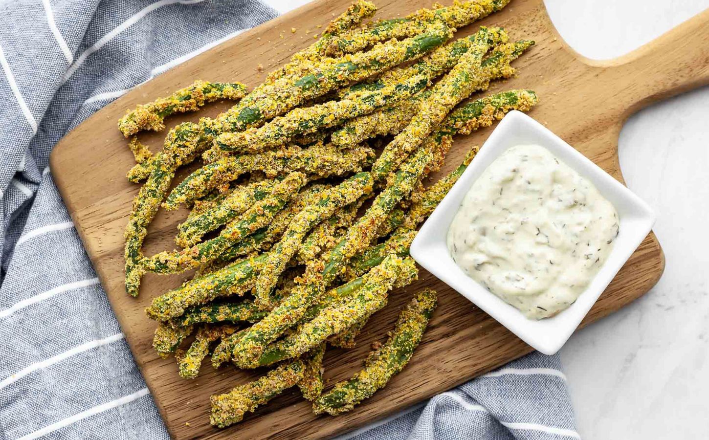 A chopping wooden board covered in oil-free green bean fries