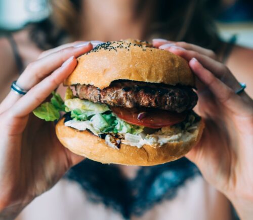 young woman holds up a burger