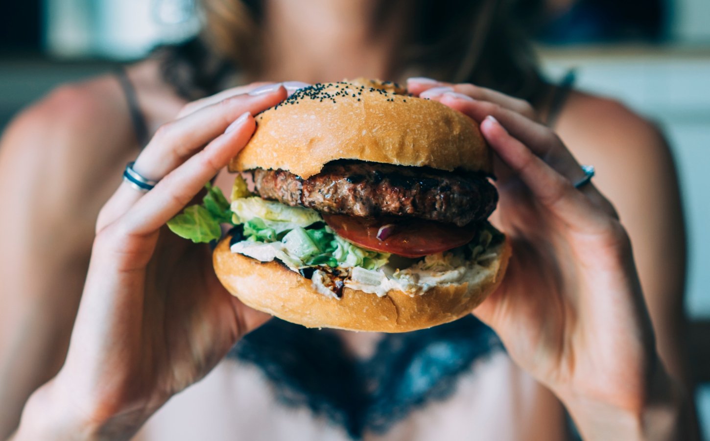 young woman holds up a burger