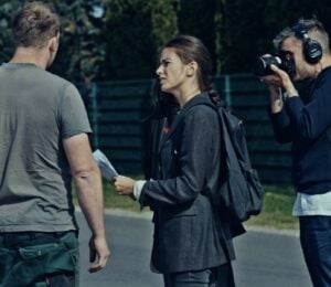 A still from new vegan documentary Food For Proft, showing a woman interviewing a man while another man holds a camera