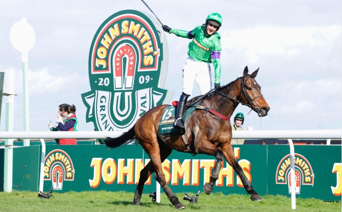 A person whipping a horse at the Grand National