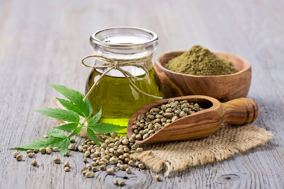 Hemp seeds next to hemp oil and a hemp leaf