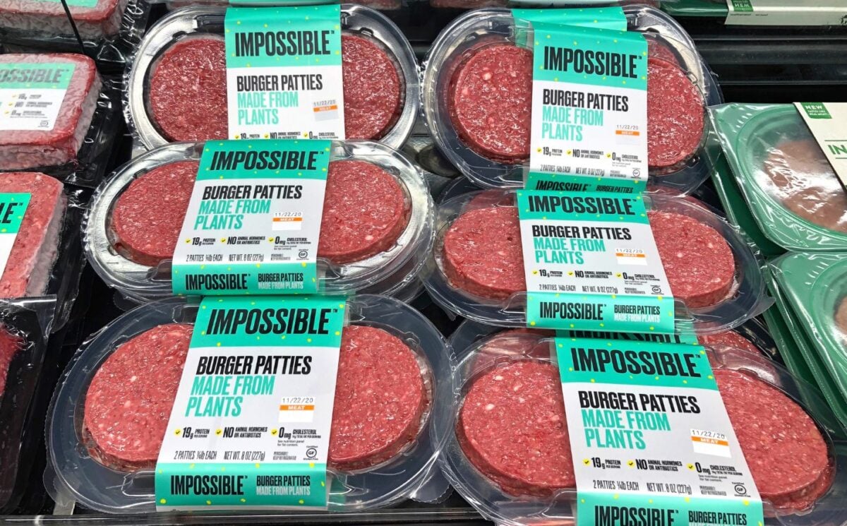 Photo shows several packages of Impossible Meat patties on display alongside animal-based proteins