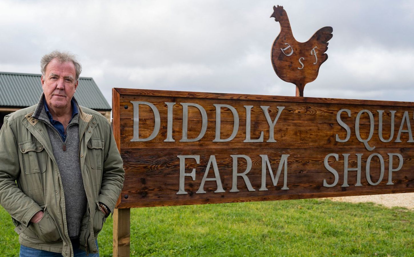 Jeremy Clarkson standing by a sign reading "Diddly Squat Farm Shop"