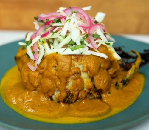 roasted cauliflower in a creamy katsu curry sauce topped with pickled onion and cabbage salad