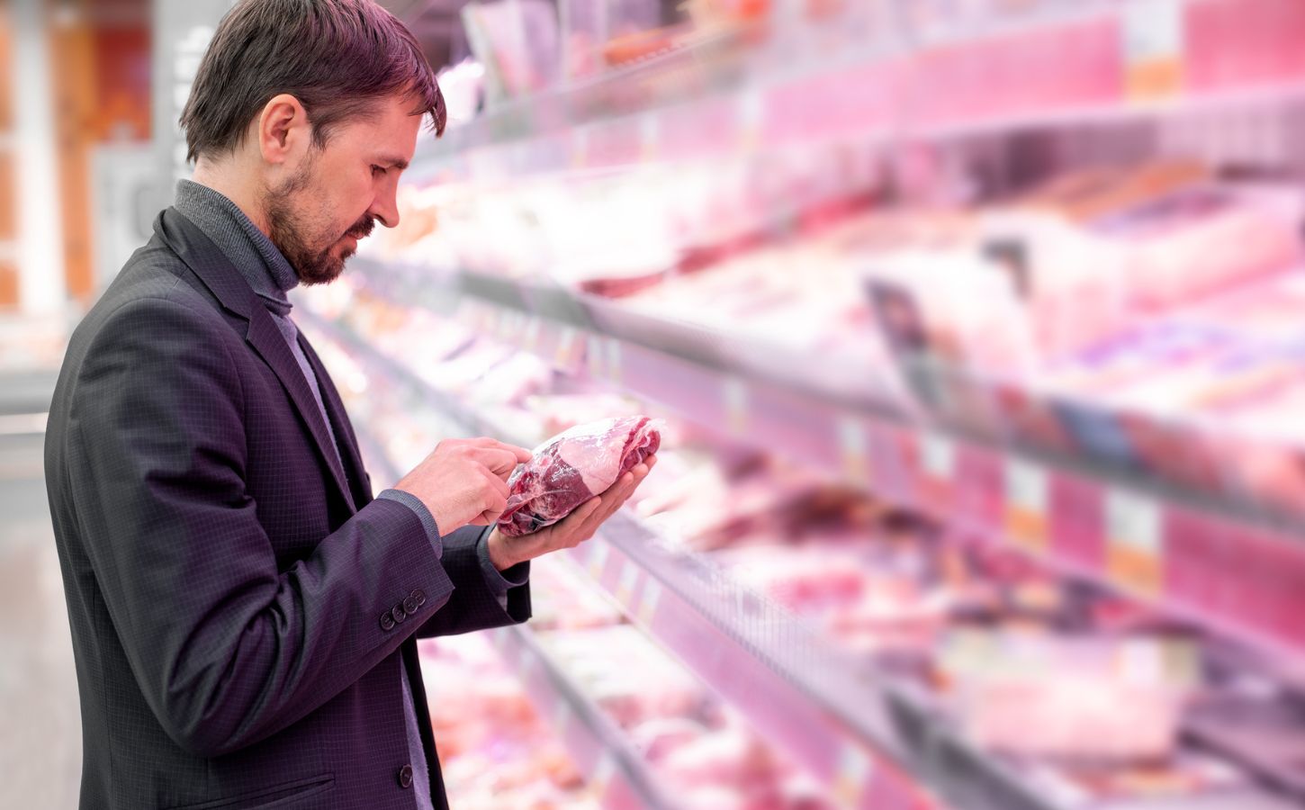 A man picking up a pack of meat in the supermarket in the UK, where meat consumption has fallen significantly