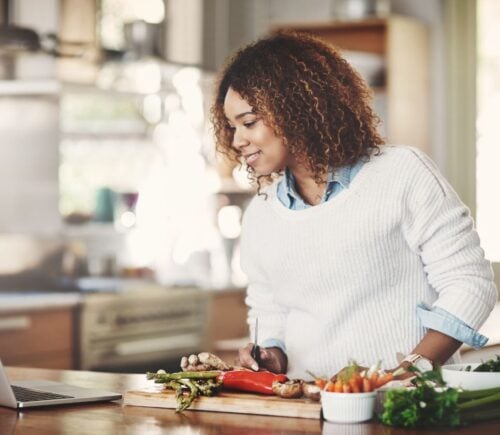 Woman researches recipes on her laptop, choosing from meat recipes or vegan recipes