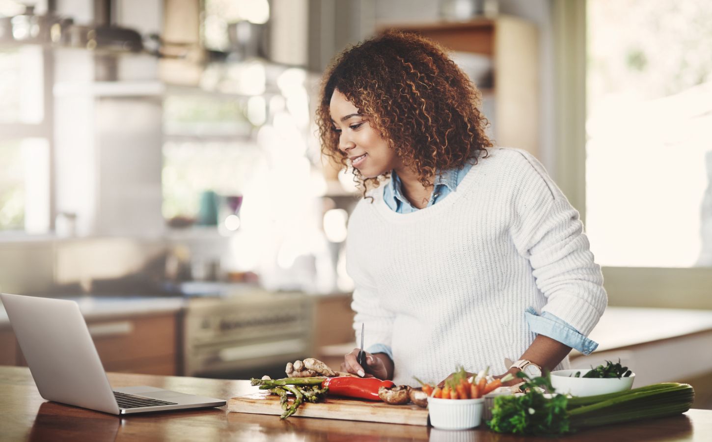 Woman researches recipes on her laptop, choosing from meat recipes or vegan recipes