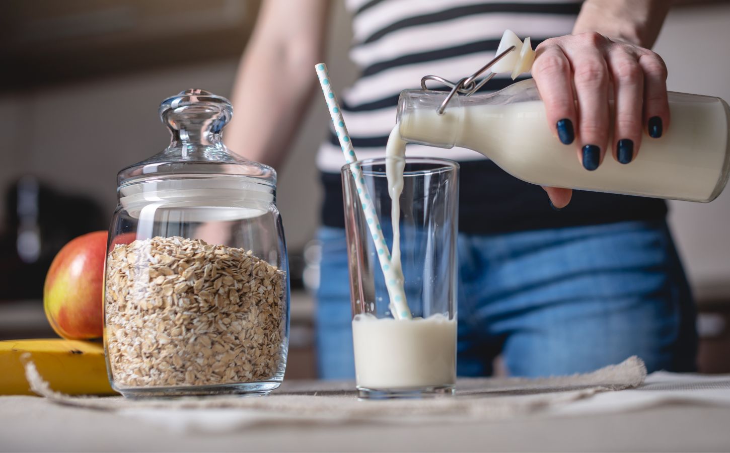 A person pouring oat milk into a glass