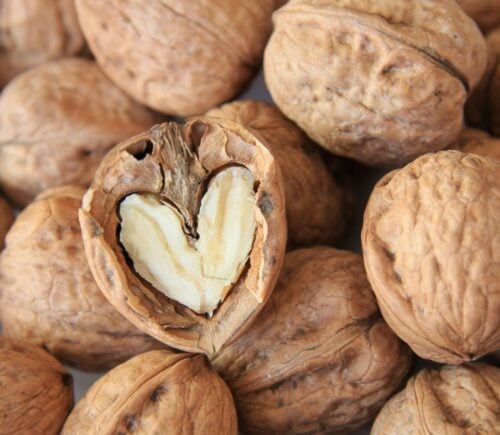 A pile of walnuts, a vegan source of omega-3, including on in the shape of a heart