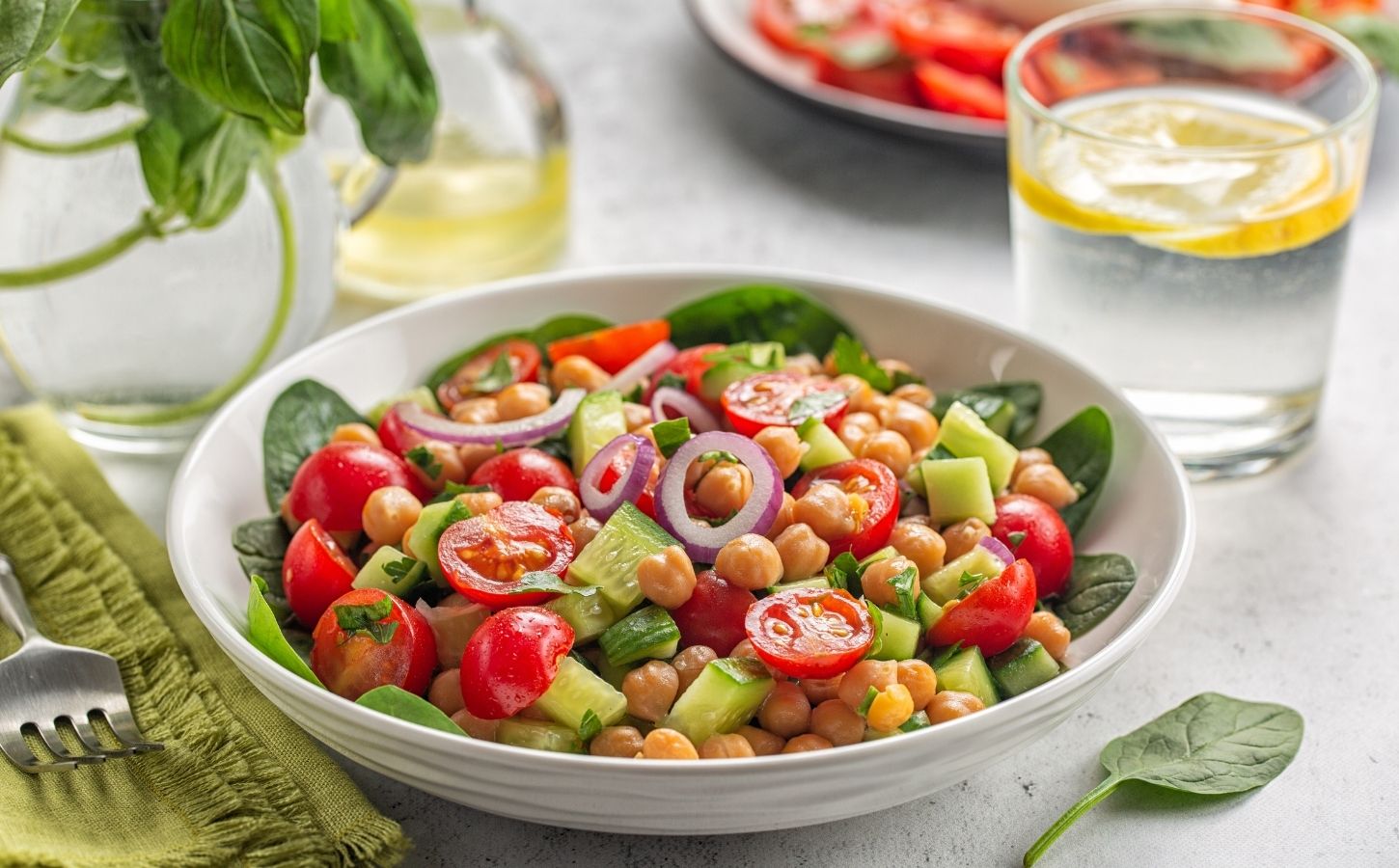 Bowl of healthy plant-based salad with vegan protein chickpeas, tomatoes and onions