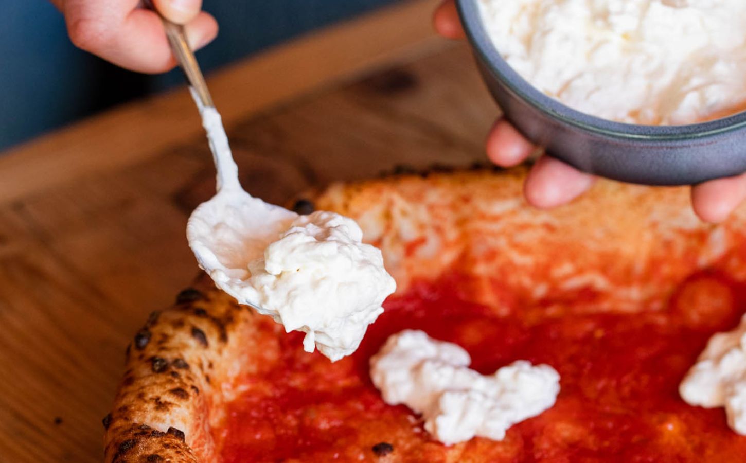 Close-up shot of vegan cheese being added to a plant-based pizza at Purezza