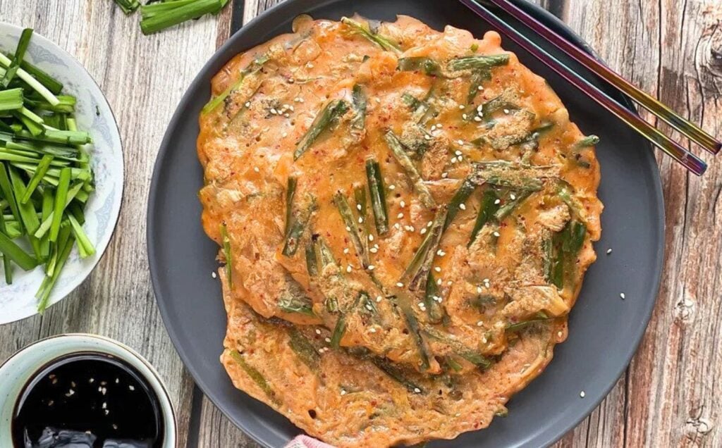 crispy vegan korean kimchi and scallion pancakes with a rich dipping sauce, presented on a black plate