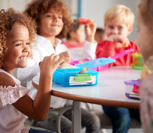 Children sitting in a school canteen eating plant-based lunches