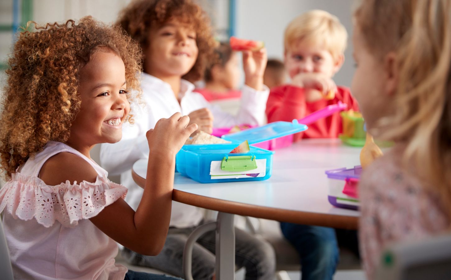 Children sitting in a school canteen eating plant-based lunches