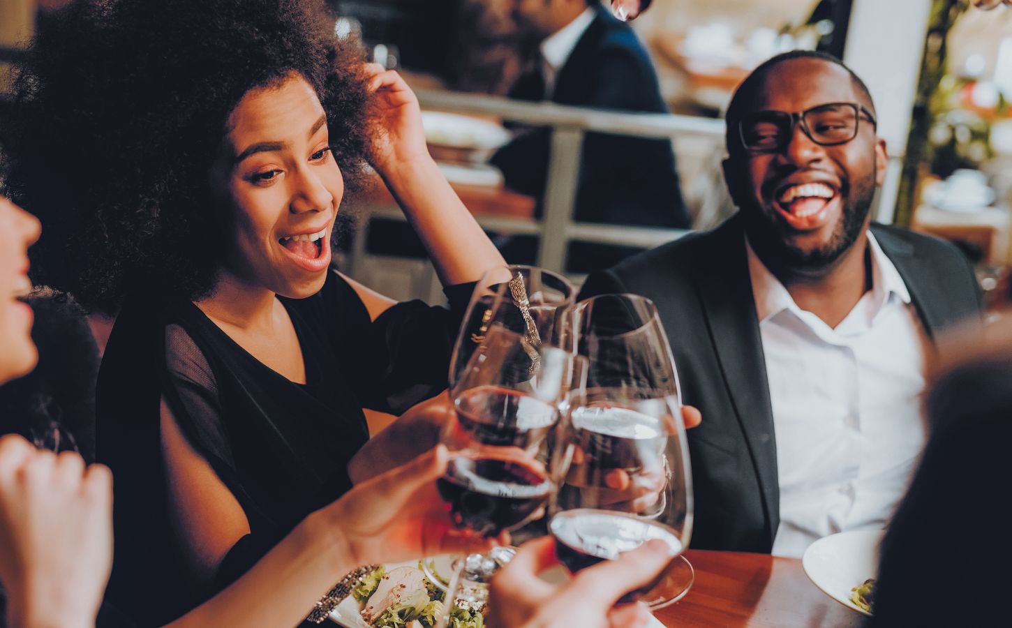 People looking happy and clinking their glasses together while eating vegan food at a US restaurant