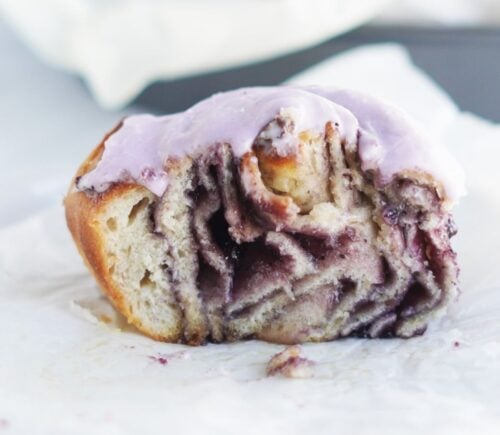 A vegan blueberry cinnamon roll from a recipe, cut in half to show all the swirls and jam inside