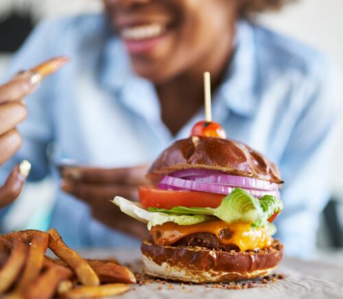 Close up of a vegan burger and chips with woman taking part in Veganuary in the background