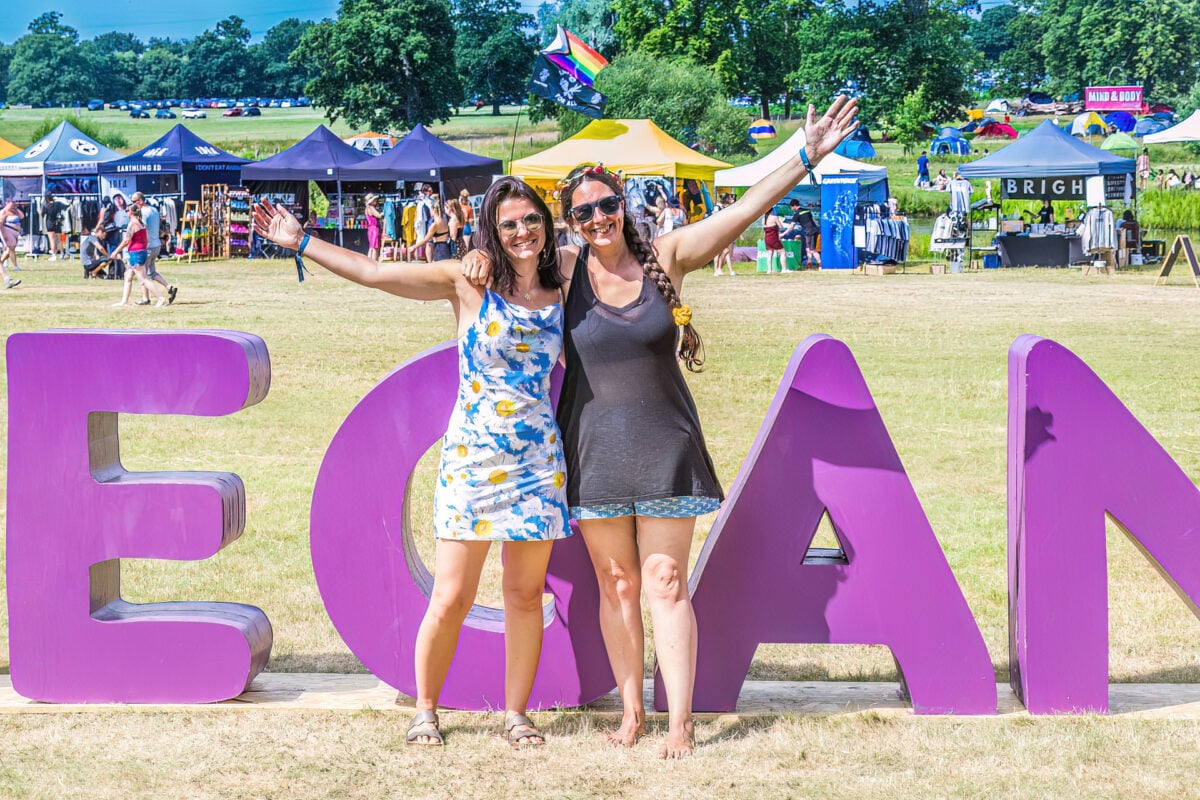 Two women standing in front of a sign reading "vegan" at Vegan Camp Out 2024