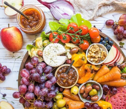 A vegan cheese platter with vegetables, chutney, and cashew cheese