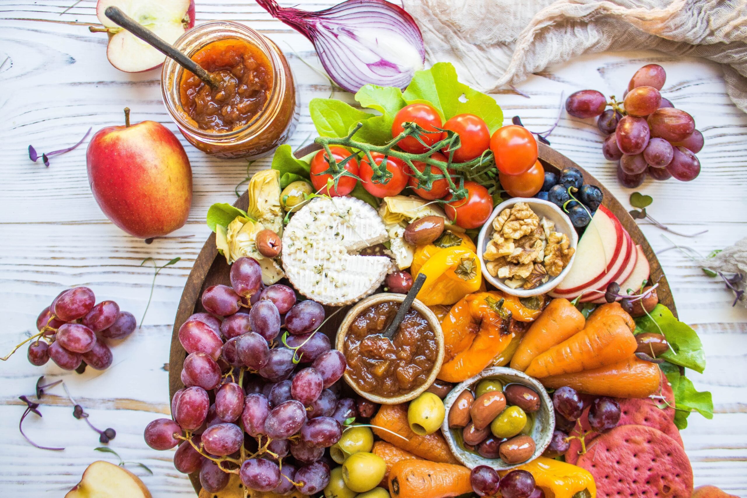 A vegan cheese platter with vegetables, chutney, and cashew cheese