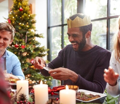 A group of friends telling jokes round a Christmas dinner table