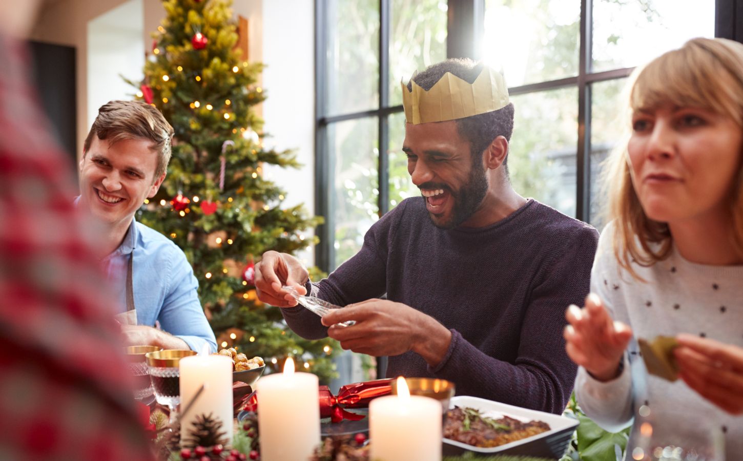 A group of friends telling jokes round a Christmas dinner table