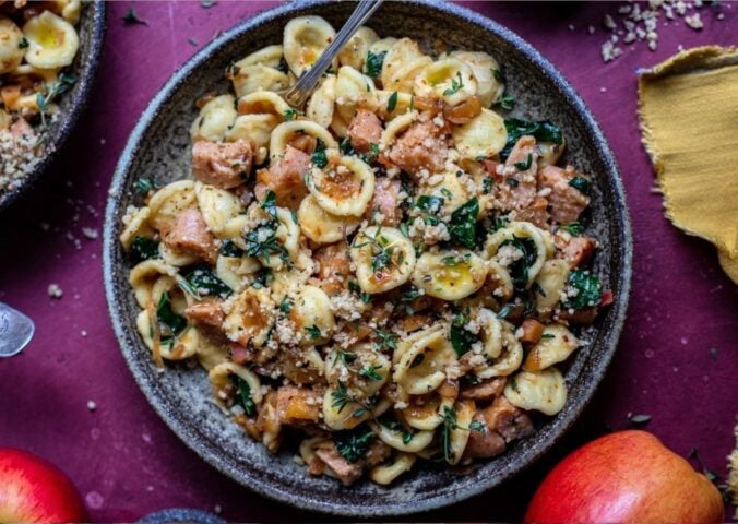 Photo shows a large bowl of sausage and kale pasta prepared using a vegan comfort food recipe.