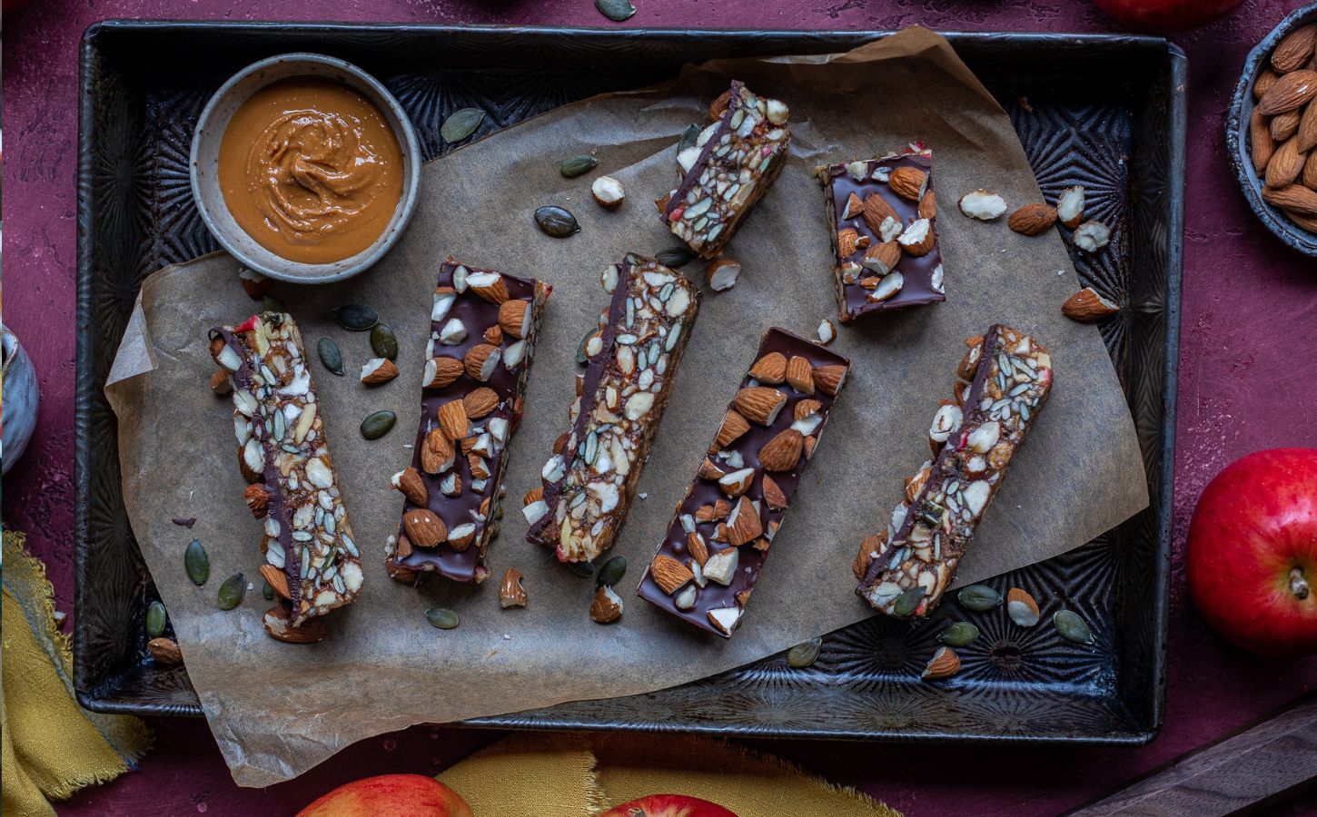 Vegan energy bars on a baking tray next to some apples and nut butter