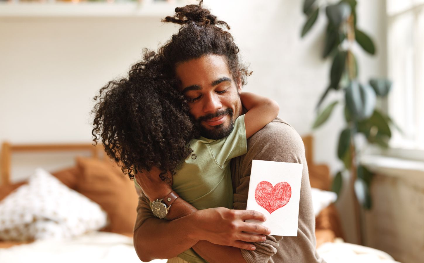 A man hugging his child holding a card with a heart on it on Father's Day