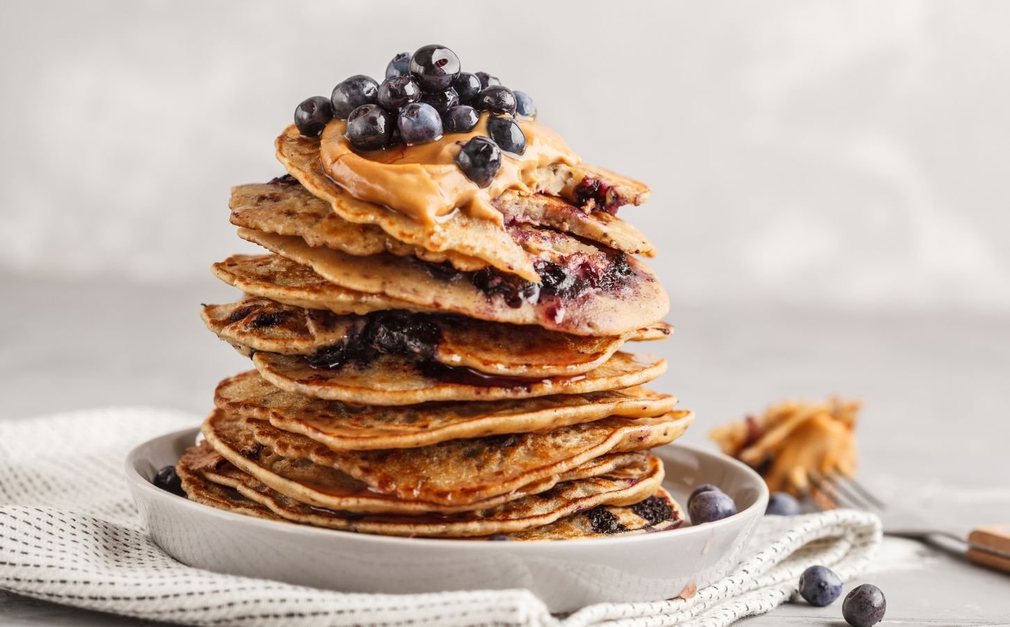 a stack of vegan blueberry pancakes with peanut butter and syrup