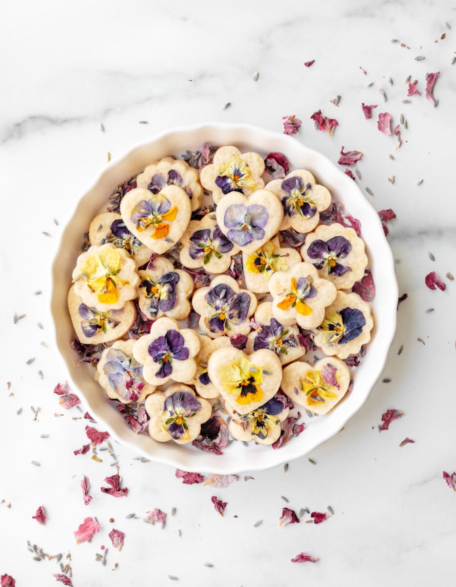 Edible shortbread biscuits in a white bowl with edible flowers on top