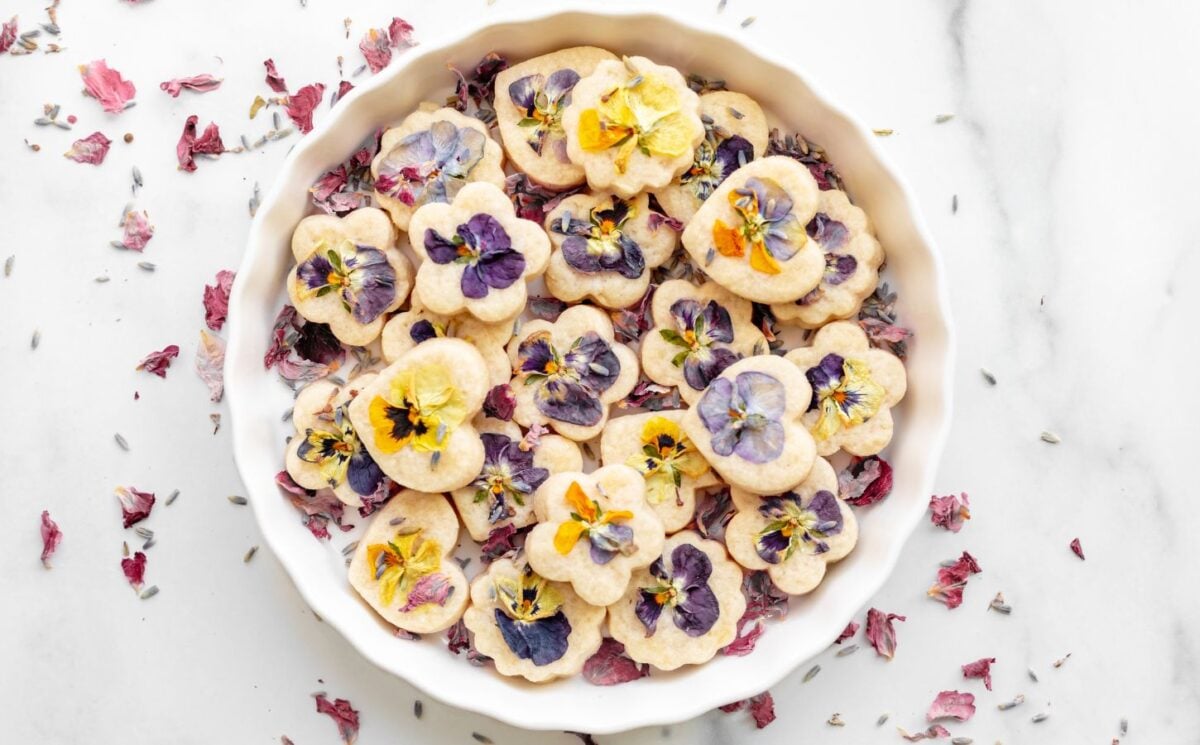 Edible shortbread biscuits in a white bowl with edible flowers on top