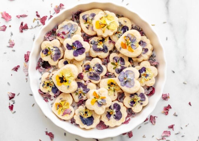 Edible shortbread biscuits in a white bowl with edible flowers on top