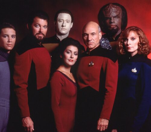 The cast of Star Trek Next Generation, said to contain vegan messaging, stood in front of a red background