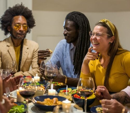 Happy vegans eating around a table celebrating Veganuary