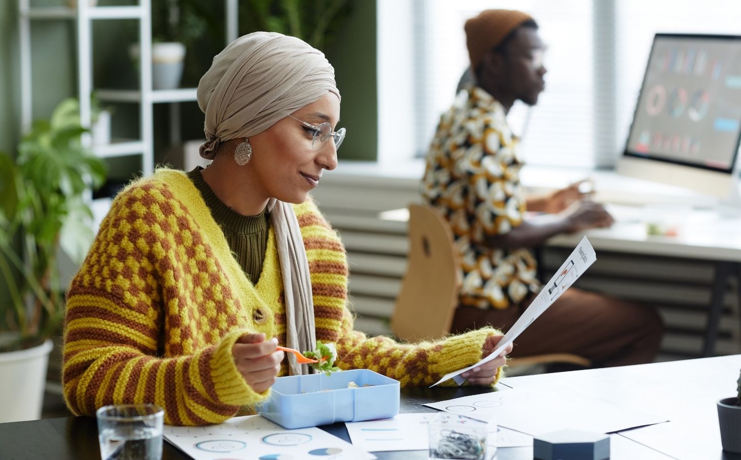 A woman sat at her desk at work eating a vegan meal