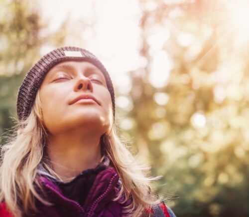 A person with their eyes closed outside in the sun, a vegan source of vitamin D