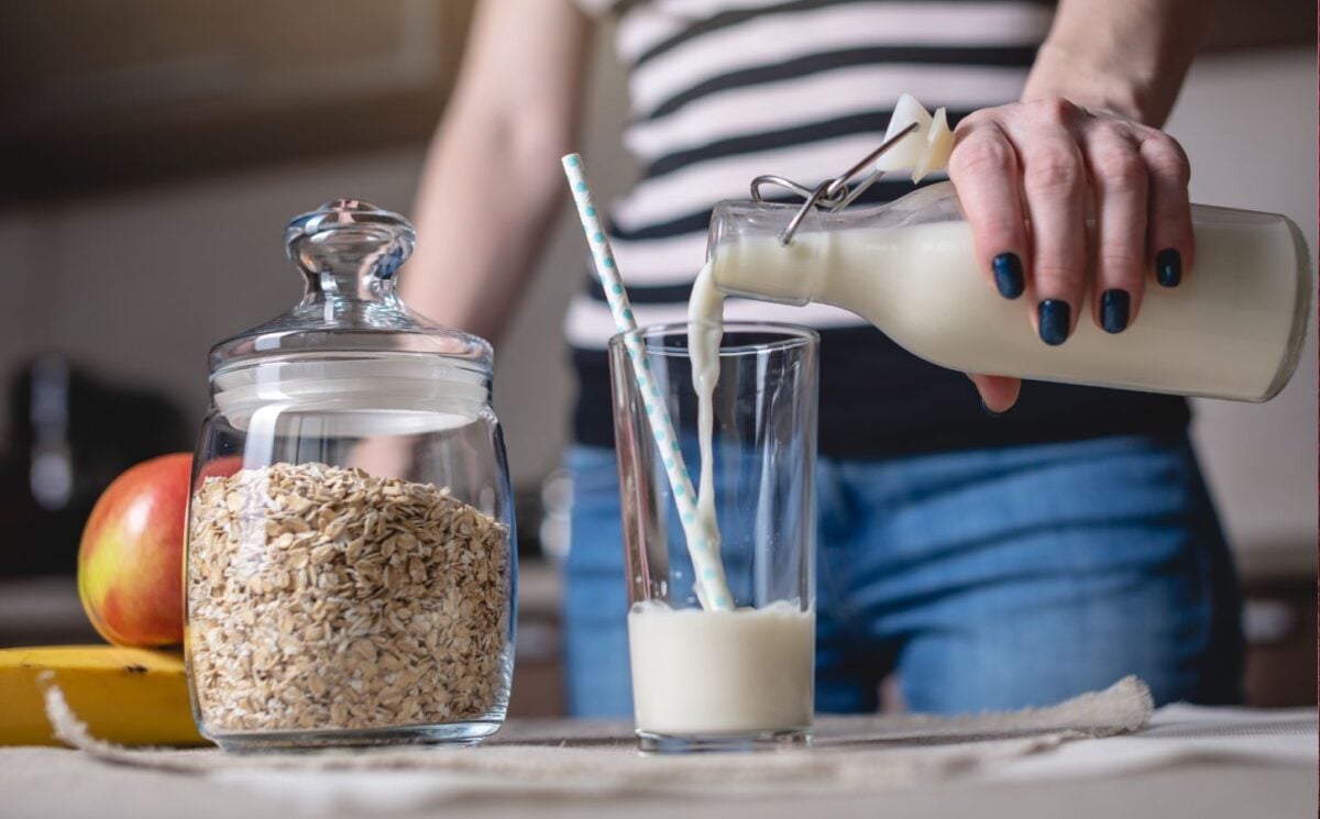 Woman pours a glass of oat milk