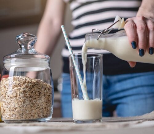 Woman pours a glass of oat milk