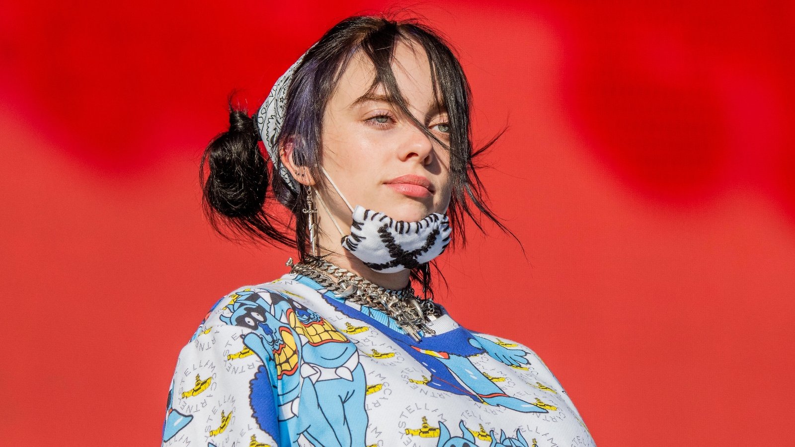 Billie Eilish on stage with a mask on her chin.